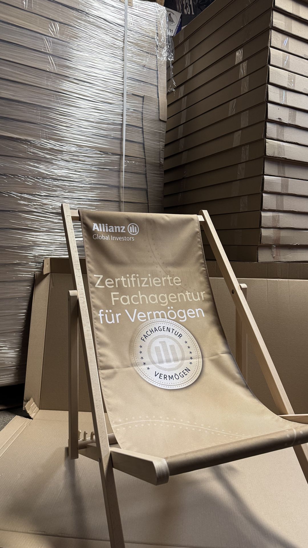 Bedruckter Liegestuhl aufgestellt vor Kartonstapeln