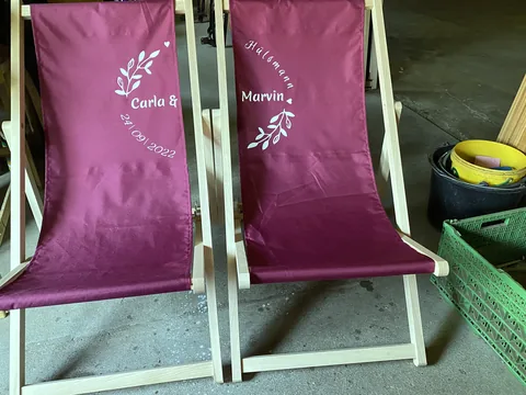Bordeauxfarbene Liegestühle mit individueller Hochzeitsgestaltung
